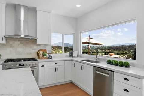 a kitchen with a sink a stove cabinets and a window
