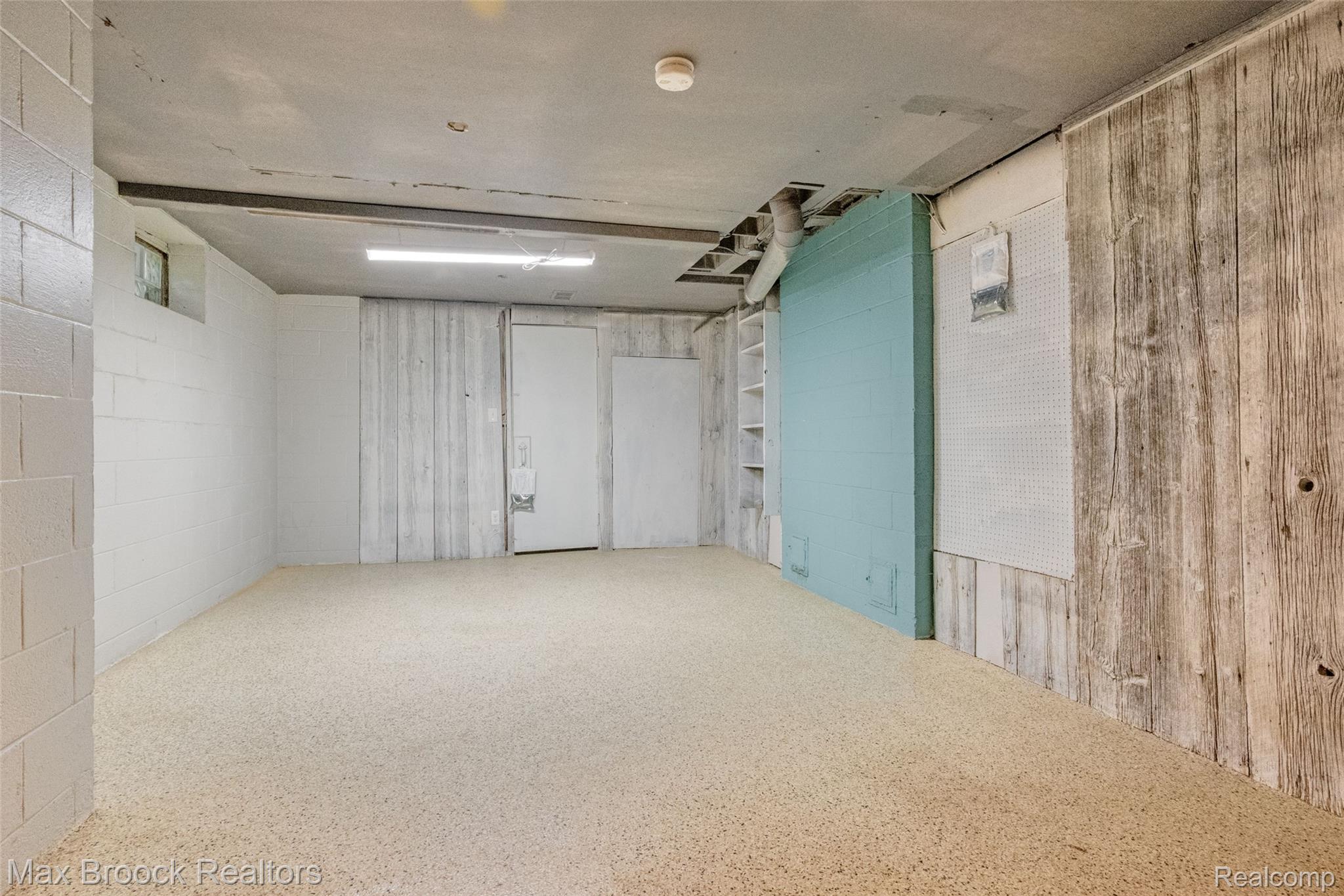 2905 Lahser Road Bloomfield Hills, MI 48304 - Photo 26 of 28 Spacious lower-level room featuring textured flooring, painted cinder block walls, and mixed wood-finish paneling