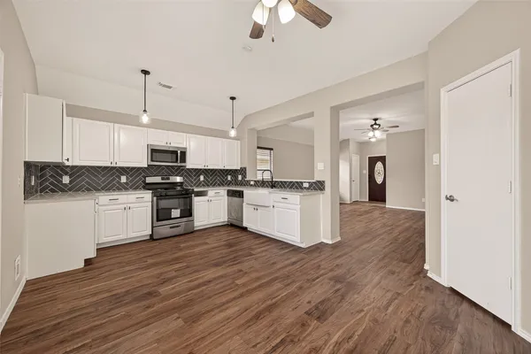 a kitchen with white cabinets stainless steel appliances and wooden floor