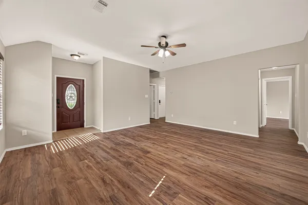 a view of an empty room with window and wooden floor