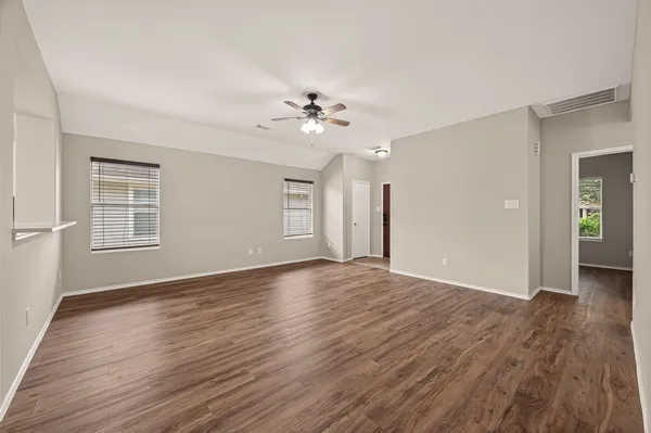 a view of an empty room with window and wooden floor