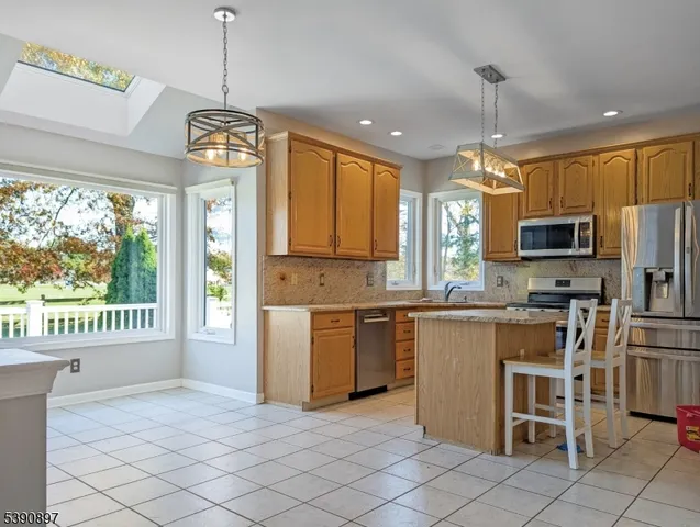 a kitchen with stainless steel appliances granite countertop a stove top oven a refrigerator a sink and a dining table