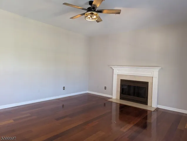 an empty room with wooden floor fireplace and windows