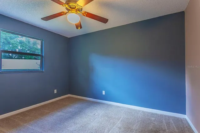 an empty room with windows and fan