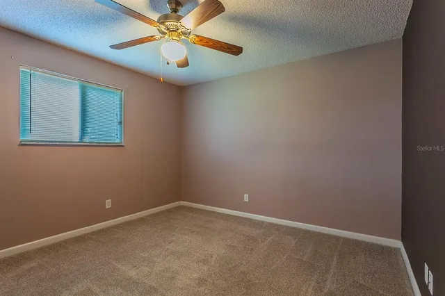 an empty room with a window and a fan