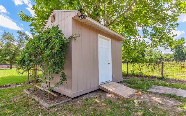 a view of a backyard with plants and large tree