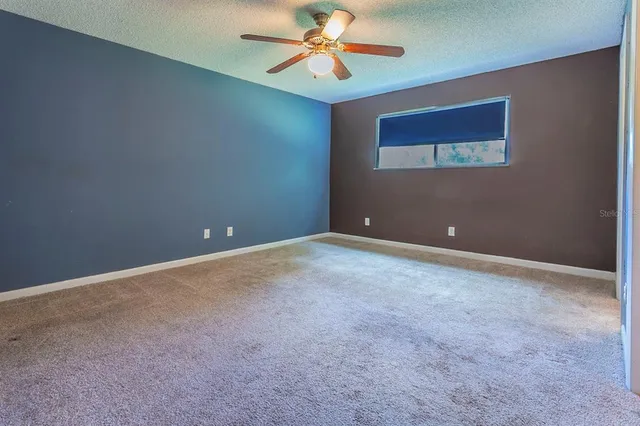 a view of an empty room with chandelier fan