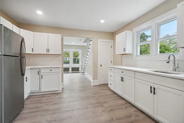 a kitchen with white cabinets and window