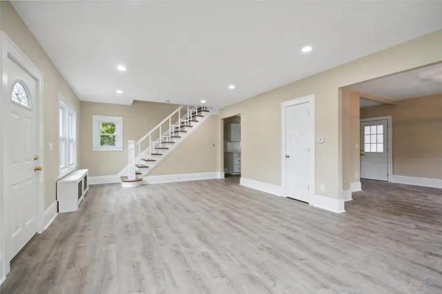 a view of an empty room with wooden floor and stairs