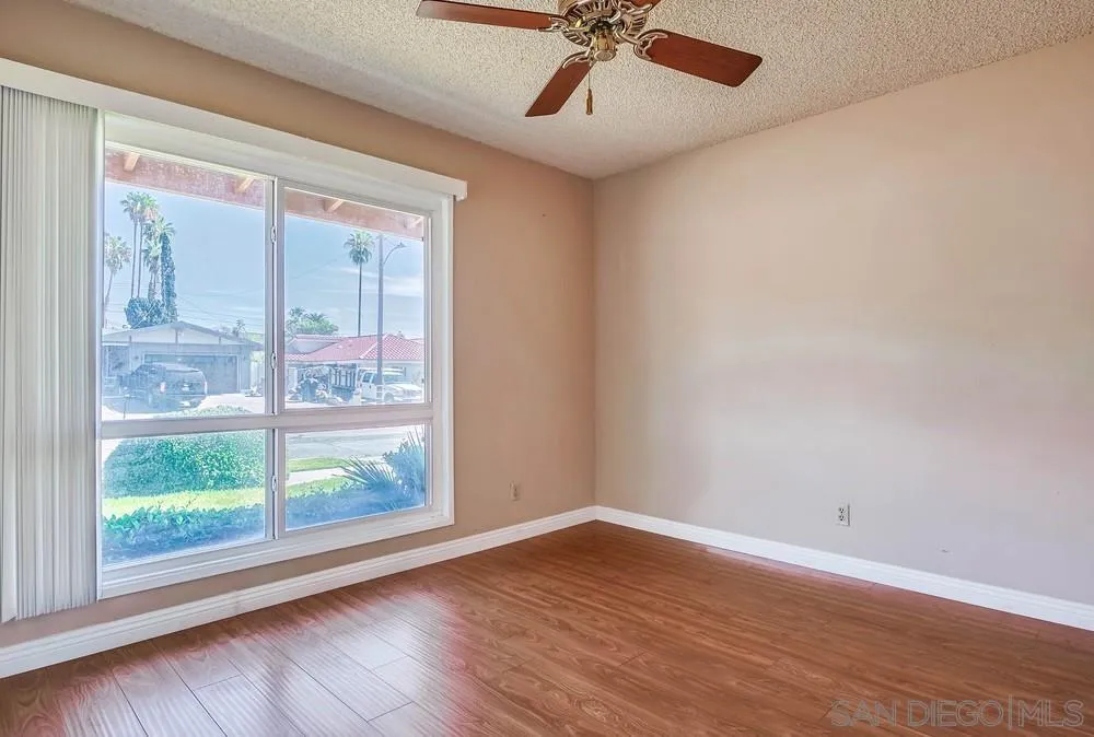 5970 Eucalyptus Drive Highland, CA 92346 - Photo 14 of 26 a view of a livingroom with a large window a ceiling fan and wooden floor