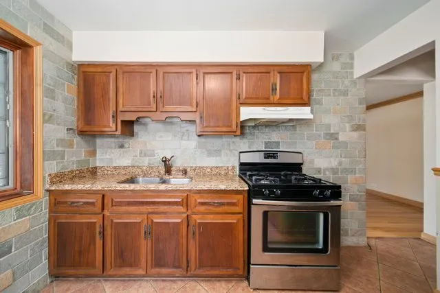 a kitchen with stainless steel appliances granite countertop a stove a sink and a microwave