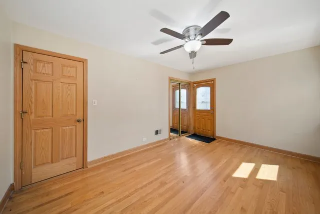 an empty room with wooden floor ceiling fan and windows
