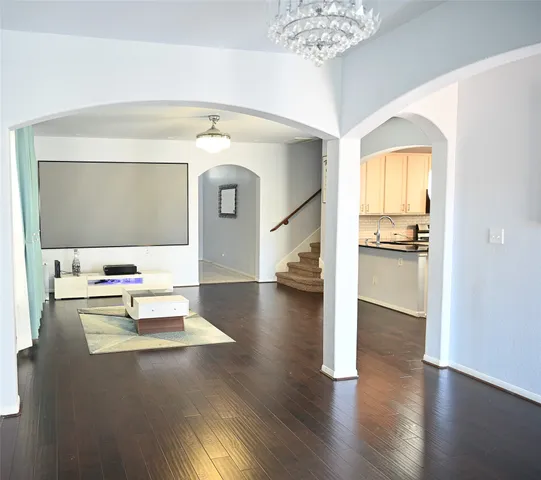 a living room with couches and potted plants with wooden floor