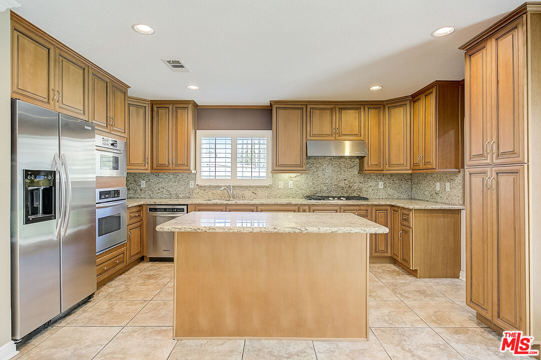 11038 Rhodesia Avenue Sunland, CA 91040 - Photo 4 of 36 a kitchen with a refrigerator a sink and cabinets