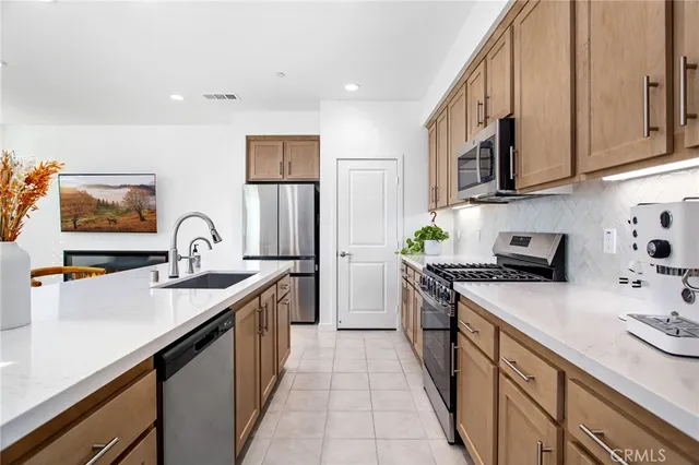 a kitchen with stainless steel appliances granite countertop a sink stove refrigerator and cabinets