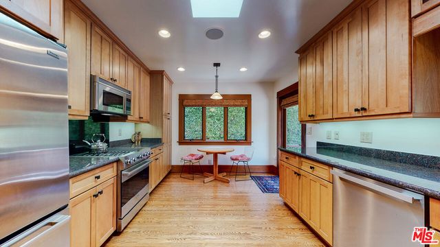 a kitchen with stainless steel appliances granite countertop a refrigerator a stove and a wooden floors