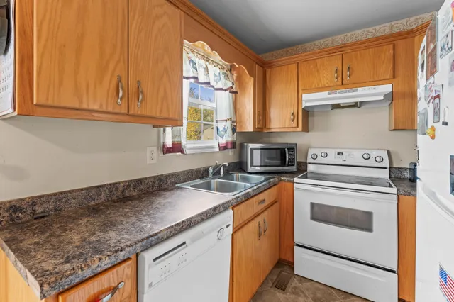 a kitchen with granite countertop a sink a stove and cabinets