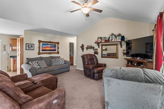 a living room with furniture a ceiling fan and a flat screen tv