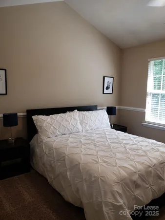 a bed sitting in a bedroom next to a window and lamp
