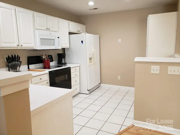 a kitchen with granite countertop white cabinets and white appliances