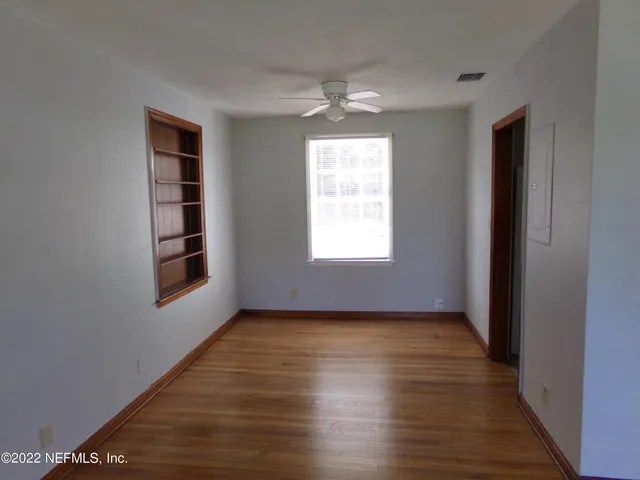 an empty room with wooden floor and windows