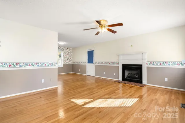 a view of empty room with wooden floor and fireplace