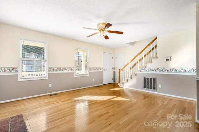a view of an empty room with window and stairs