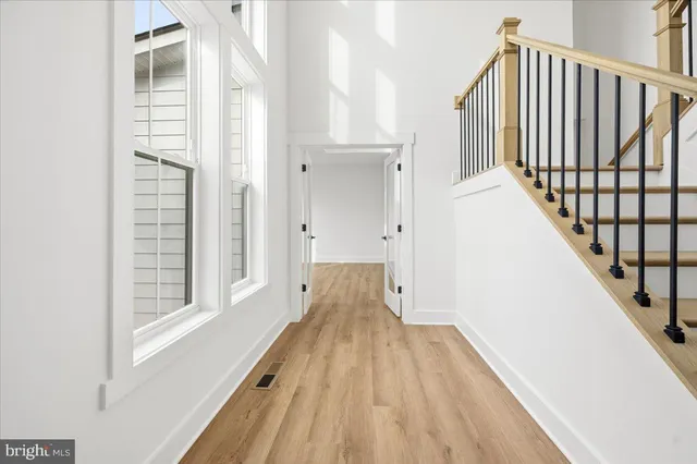 a view of an empty room with window and wooden floor