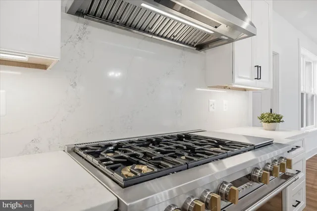 an empty room with wooden floor chandelier fan and windows