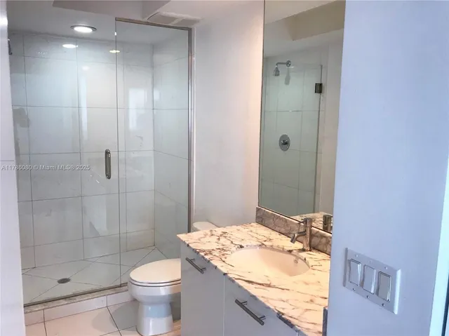 a bathroom with a granite countertop sink a toilet and shower