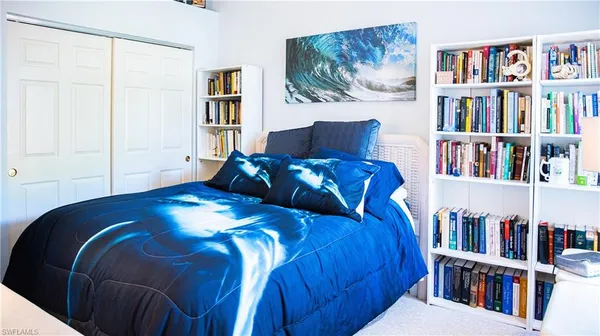 a bedroom with a large bed a book shelf and a painting on the wall
