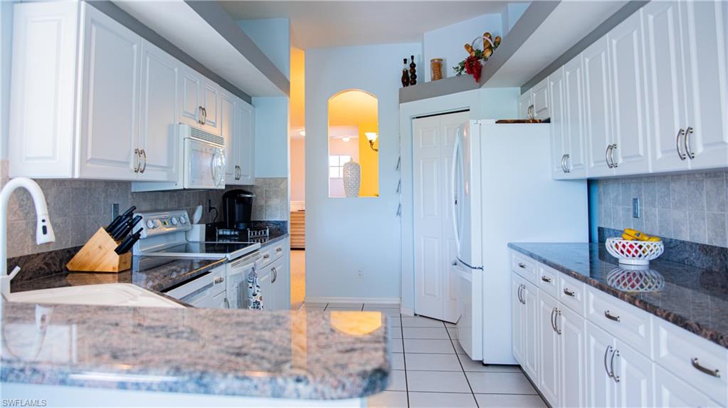 10711 Crooked River Road, Unit 202 Estero, FL 34135 - Photo 10 of 28 a kitchen with stainless steel appliances granite countertop a sink a stove a refrigerator and white cabinets