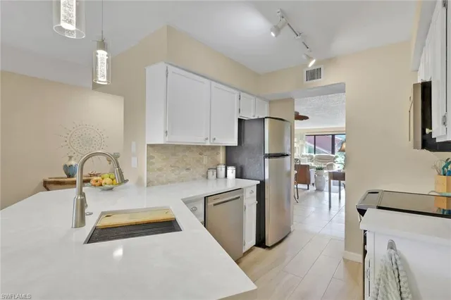 a kitchen with stainless steel appliances granite countertop a refrigerator sink and white cabinets