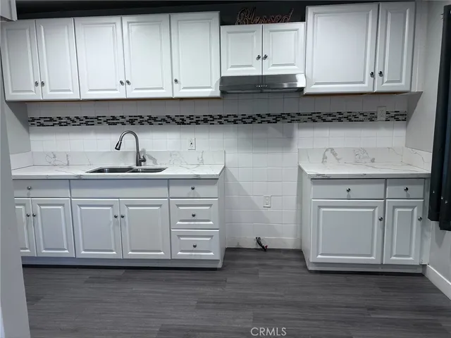 a kitchen with white cabinets and sink