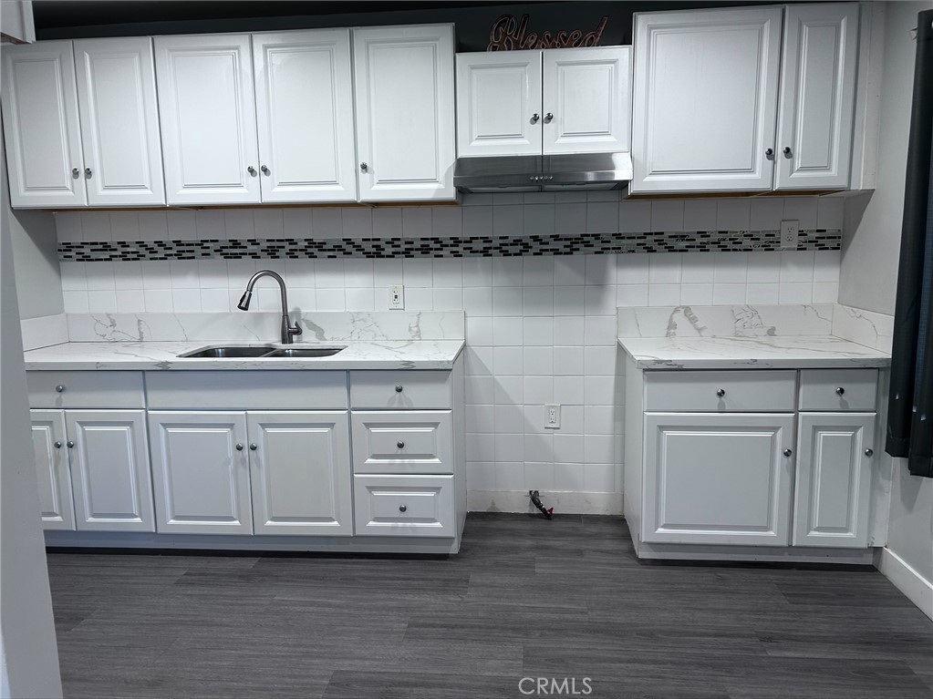a kitchen with white cabinets and sink