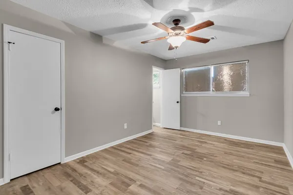 a view of an empty room with window and wooden floor