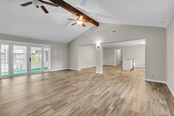 a view of empty room with wooden floor and fan