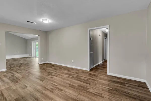 a view of an empty room with wooden floor and closet