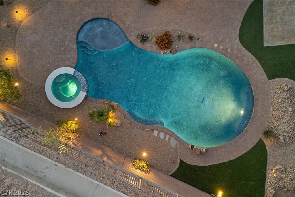 2125 De Rouge Avenue Henderson, NV 89044 - Photo 92 of 96 An illuminated backyard oasis featuring a free-form pool and integrated spa, perfect for evening enjoyment.