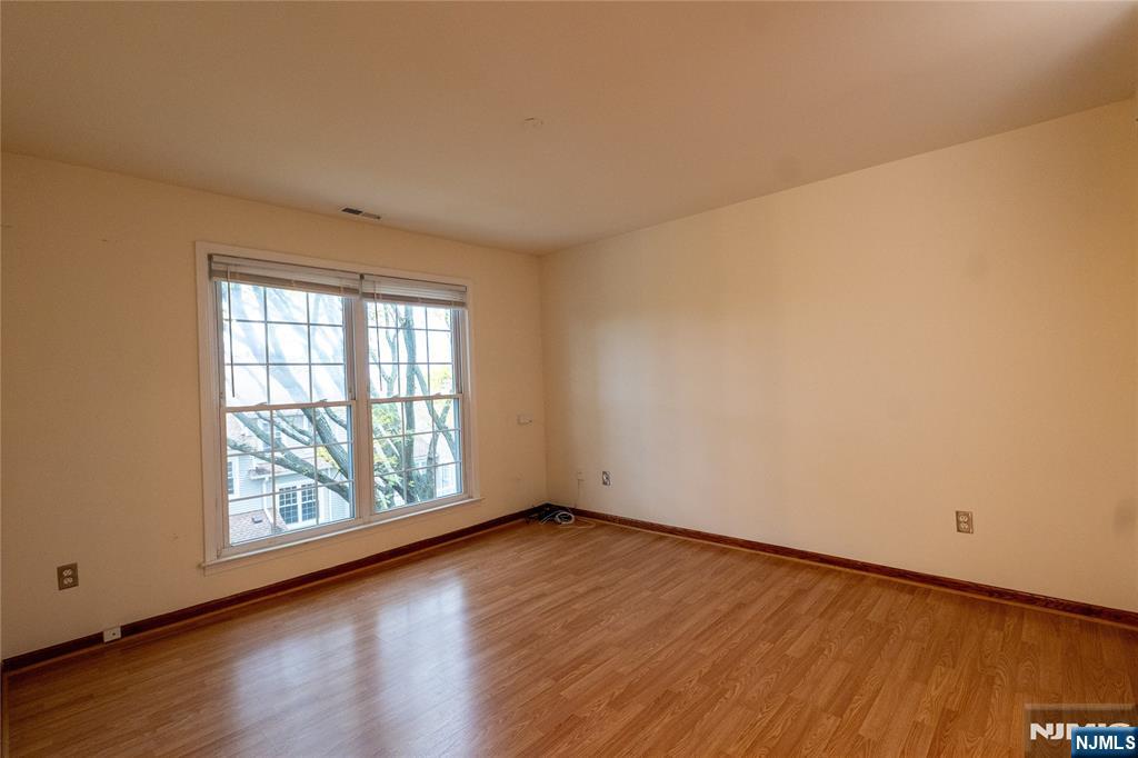 56 Fox Run Drive, Unit 56 Englewood, NJ 07631 - Photo 12 of 31 an empty room with wooden floor and windows with curtains