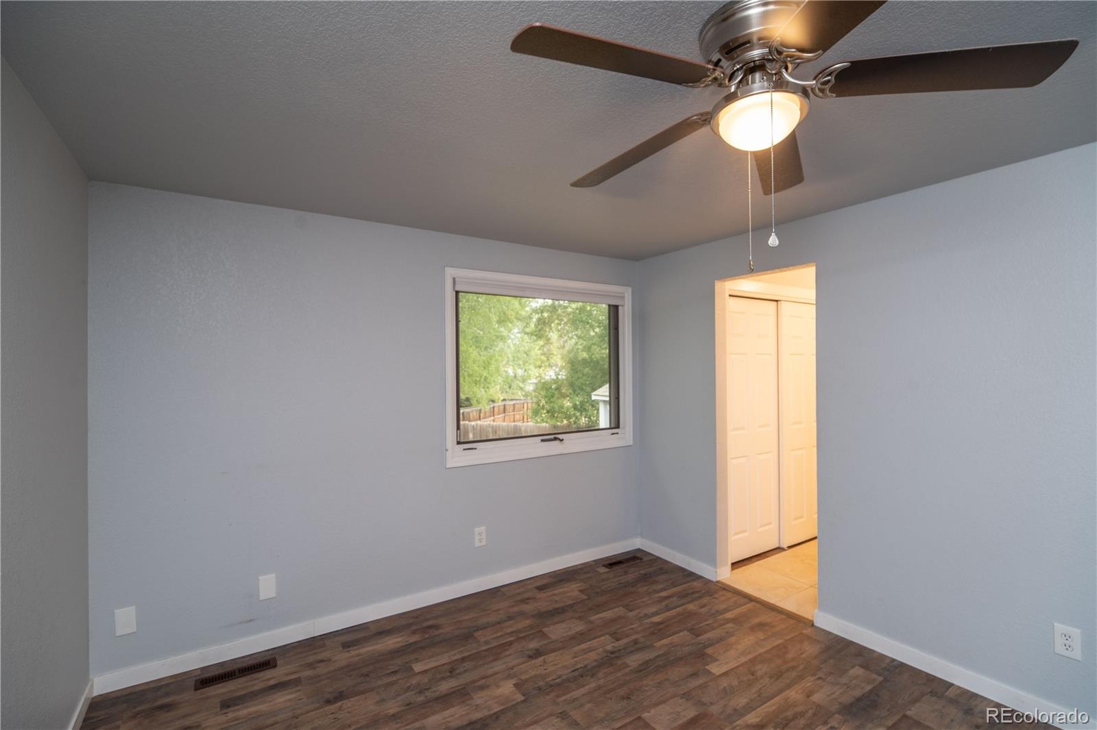 10879 West 65th Way Arvada, CO 80004 - Photo 18 of 41 an empty room with wooden floor fan and windows