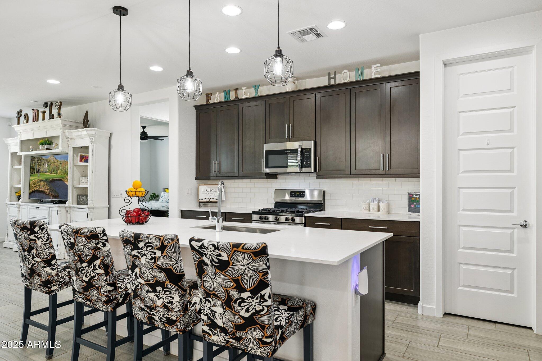 a kitchen with stainless steel appliances kitchen island granite countertop a stove a sink and a microwave