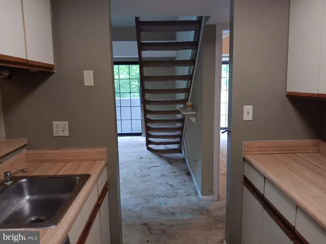 a view of a kitchen with granite countertop white cabinets and a wooden floor