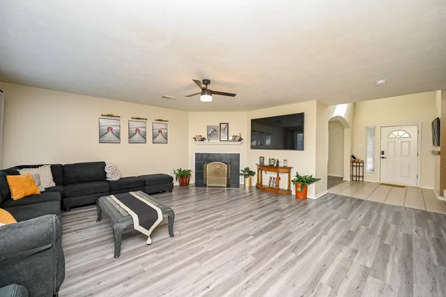 a dining room with wooden floor a chandelier fan a wooden table and chairs