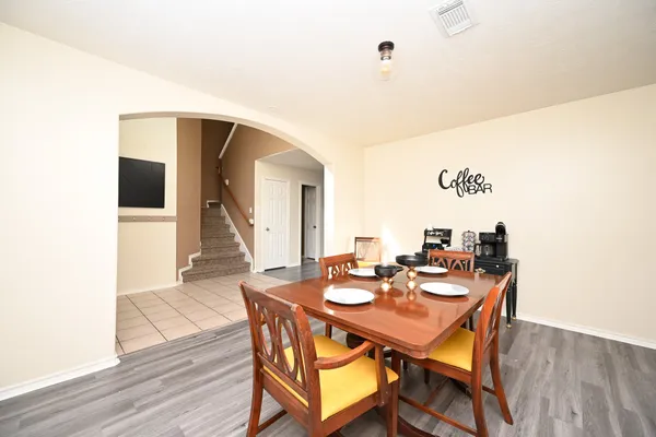 a dining room with wooden floor a chandelier fan a wooden table and chairs