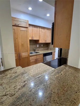 a large kitchen with kitchen island granite countertop a refrigerator sink and cabinets