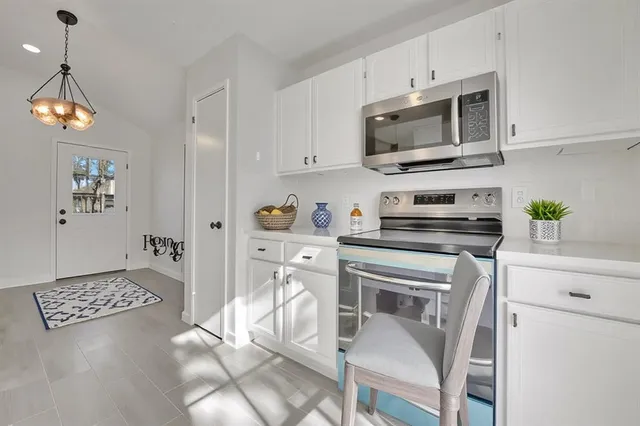 a kitchen with stainless steel appliances granite countertop a stove a microwave a refrigerator a sink a dining table and chairs with wooden floor