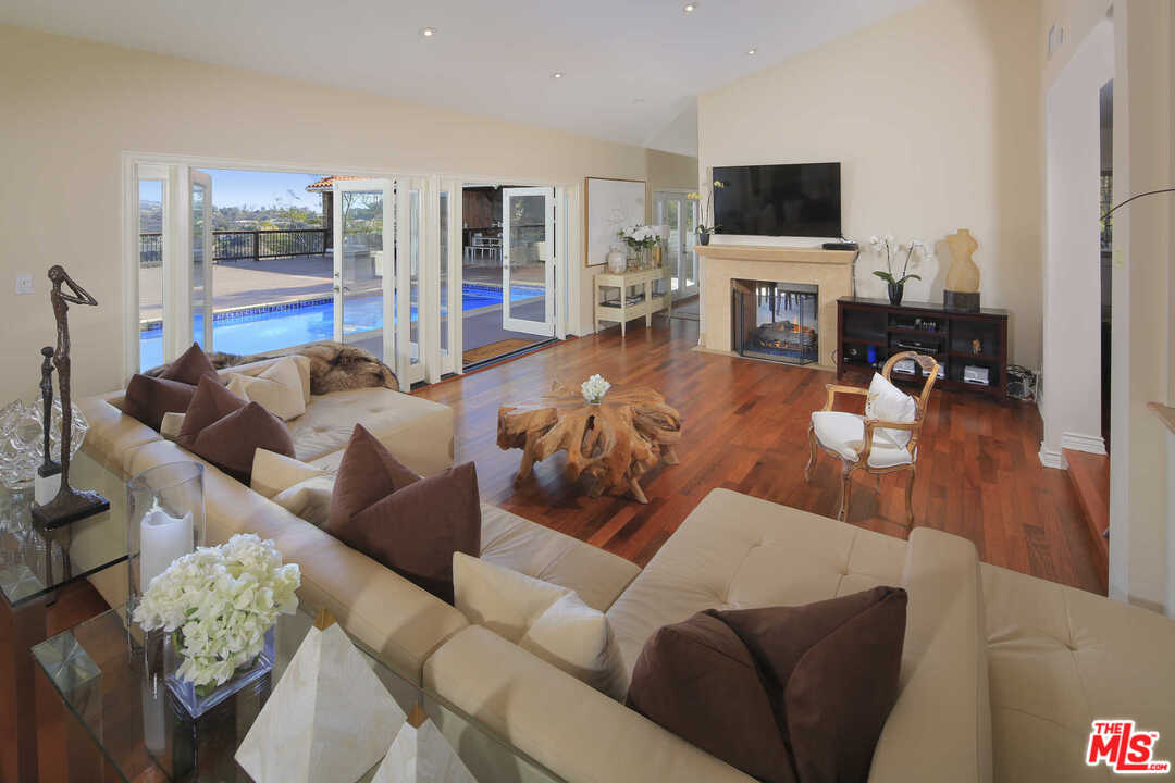 1410 Stradella Road Los Angeles, CA 90077 - Photo 8 of 24 a living room with furniture a flat screen tv and a fireplace