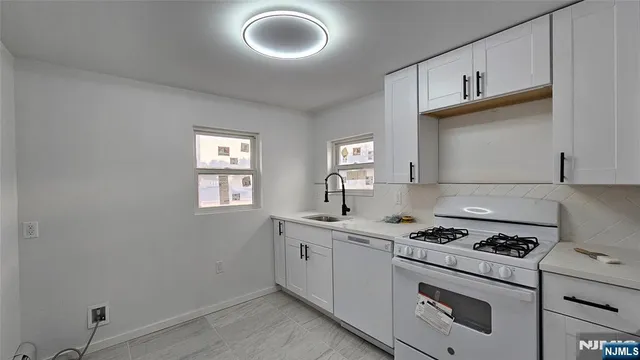 a kitchen with granite countertop a stove a sink and a microwave