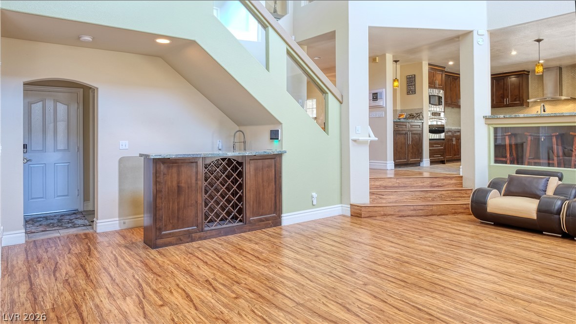 3704 North Campbell Road Las Vegas, NV 89129 - Photo 21 of 38 Warm wood flooring flows through this inviting living space, connecting to a built-in wet bar and a well-appointed kitchen.